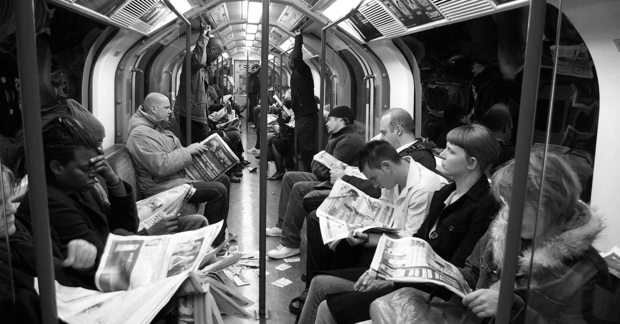 Passengers reading newspapers on a crowded London Underground train