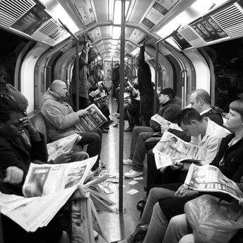 Passengers reading newspapers on a crowded London Underground train