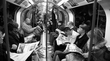 Passengers reading newspapers on a crowded London Underground train