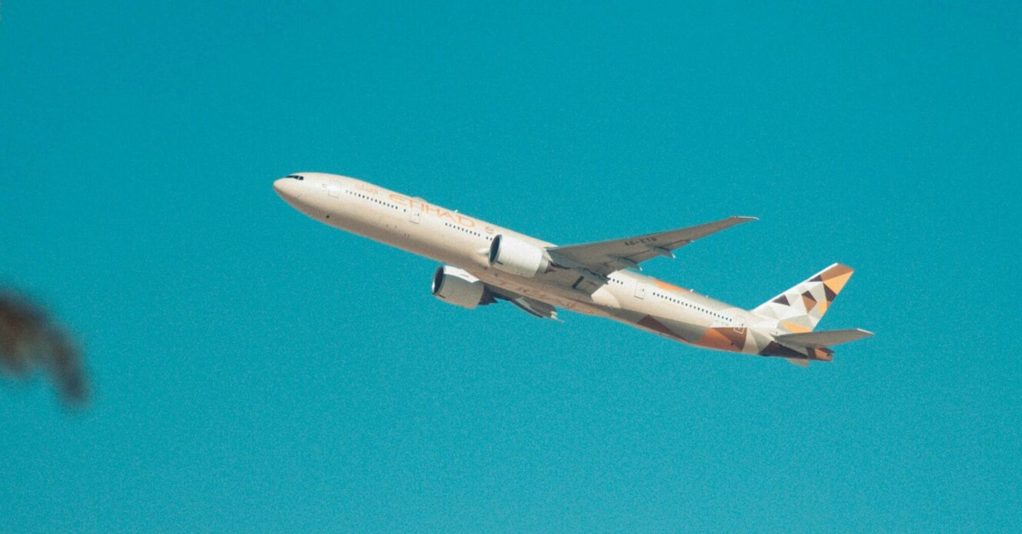 Etihad Airways plane taking off against a clear blue sky