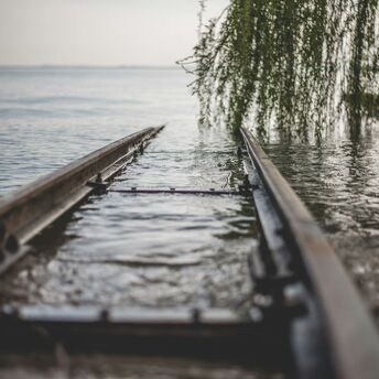 Flooded railway track submerged in water near a tree branch
