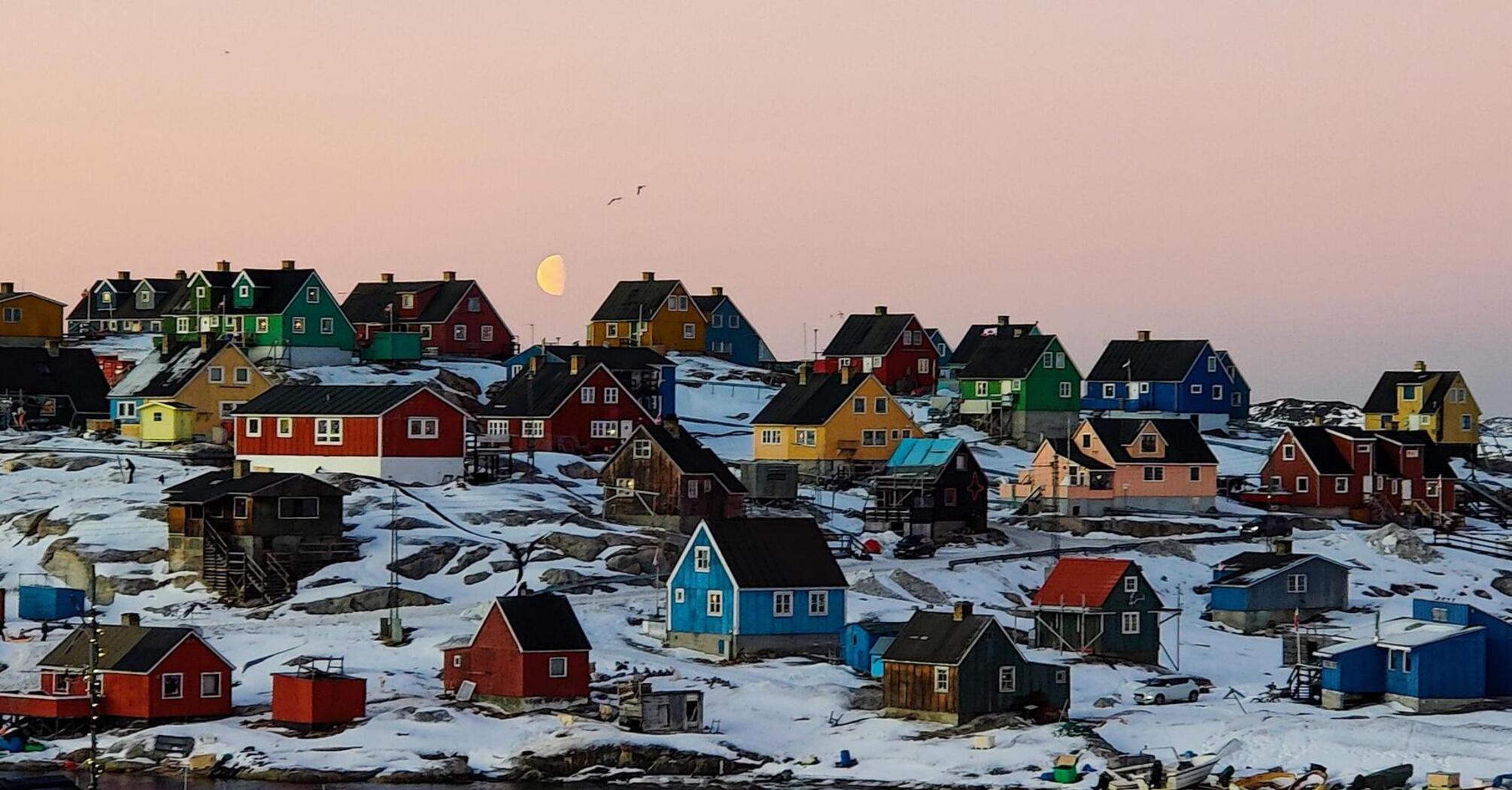 Colorful houses in a snow-covered Greenlandic village at sunset