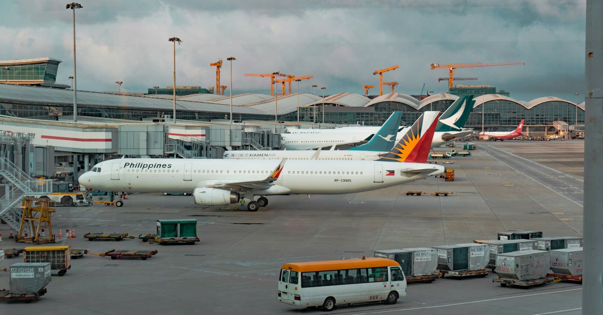 Airplanes of Philippine Airlines parked at an airport terminal, with other aircraft and service vehicles in the background