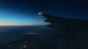 Nighttime view of an airplane wing over a lit-up city below