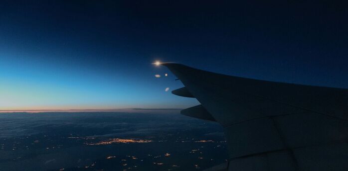 Nighttime view of an airplane wing over a lit-up city below