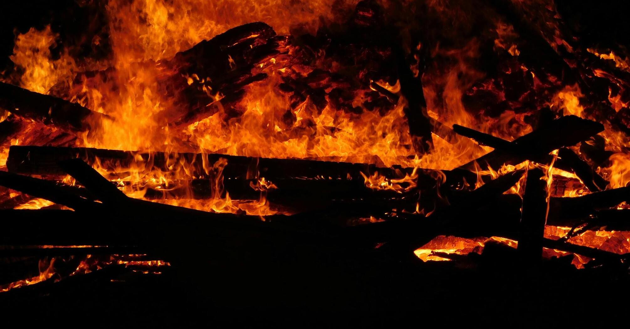 Raging fire consuming wooden structures at night