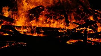 Raging fire consuming wooden structures at night
