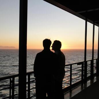 Two passengers looking at the sunset from a cruise ship deck