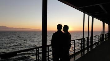 Two passengers looking at the sunset from a cruise ship deck