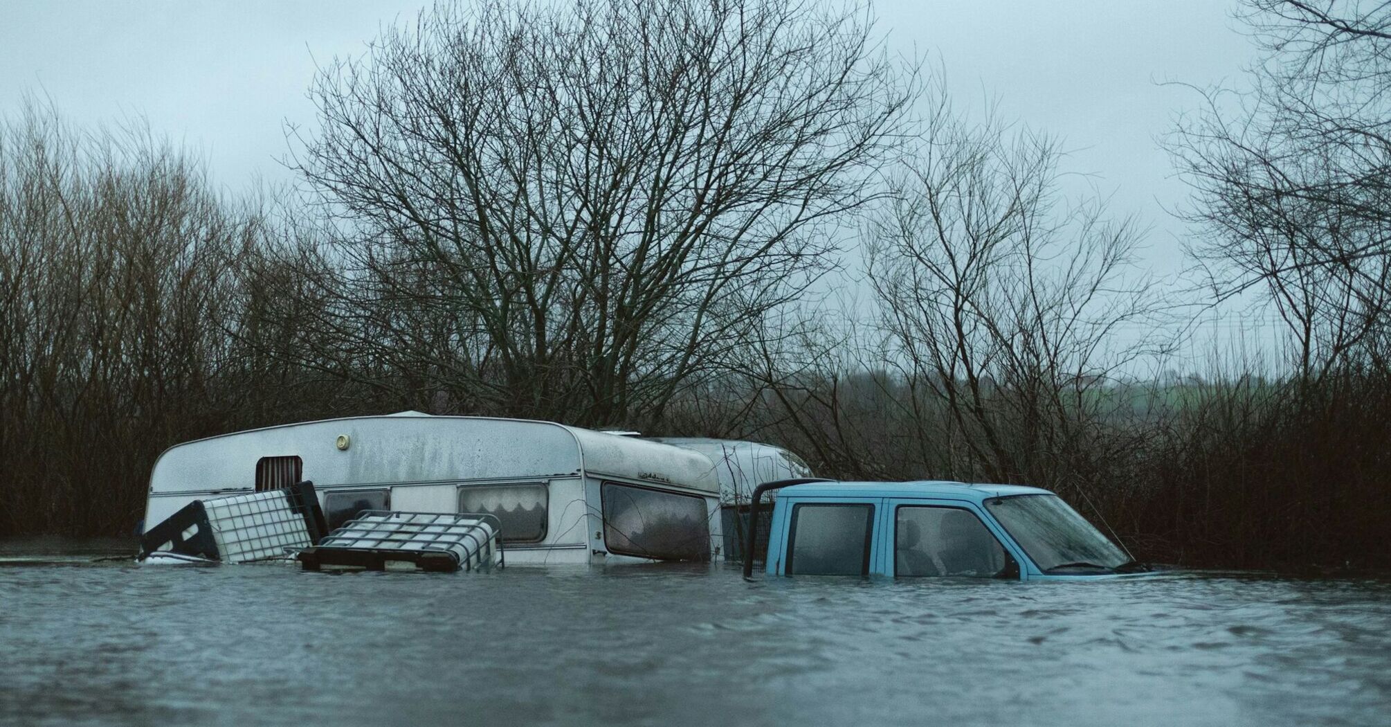 A flooded caravan and vehicle submerged in water after heavy rainfall