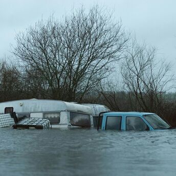A flooded caravan and vehicle submerged in water after heavy rainfall