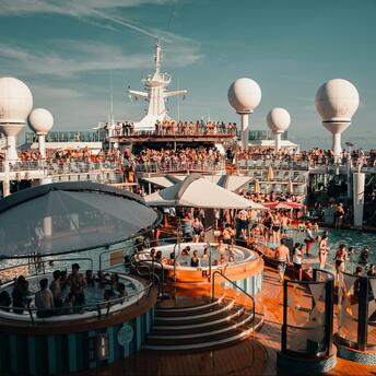Guests enjoying pools and entertainment aboard a cruise ship during a lively event