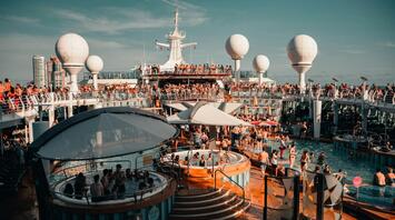 Guests enjoying pools and entertainment aboard a cruise ship during a lively event