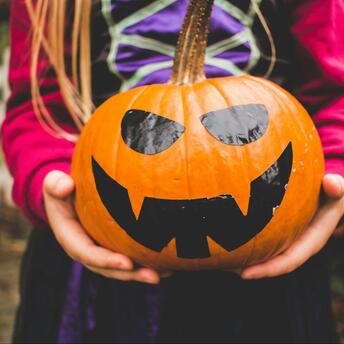 Child holding a carved pumpkin with a spooky face
