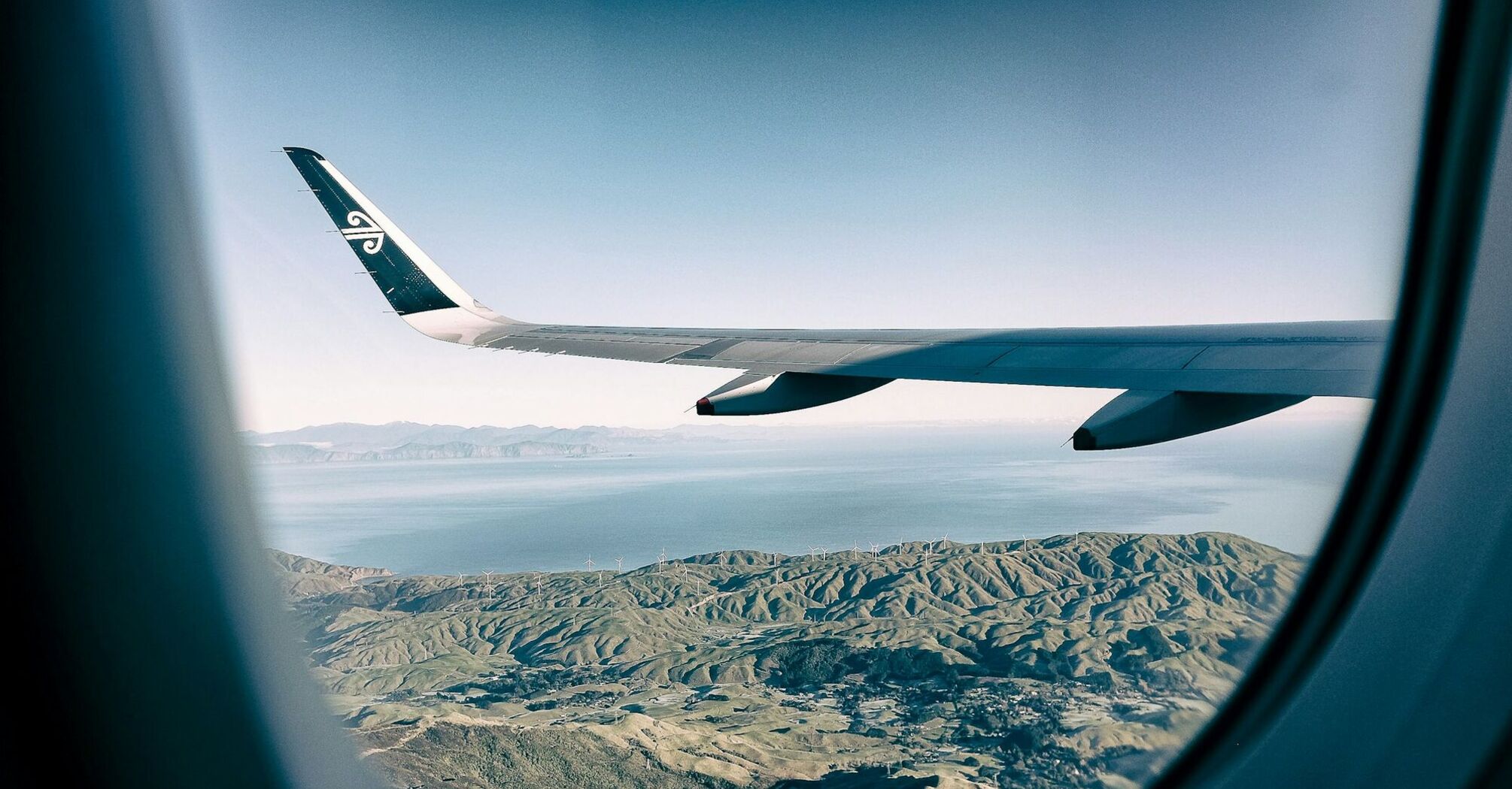 Air New Zealand wing over scenic landscape viewed from airplane window