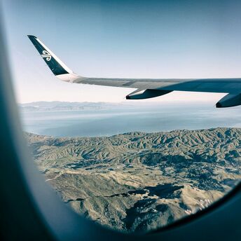 Air New Zealand wing over scenic landscape viewed from airplane window