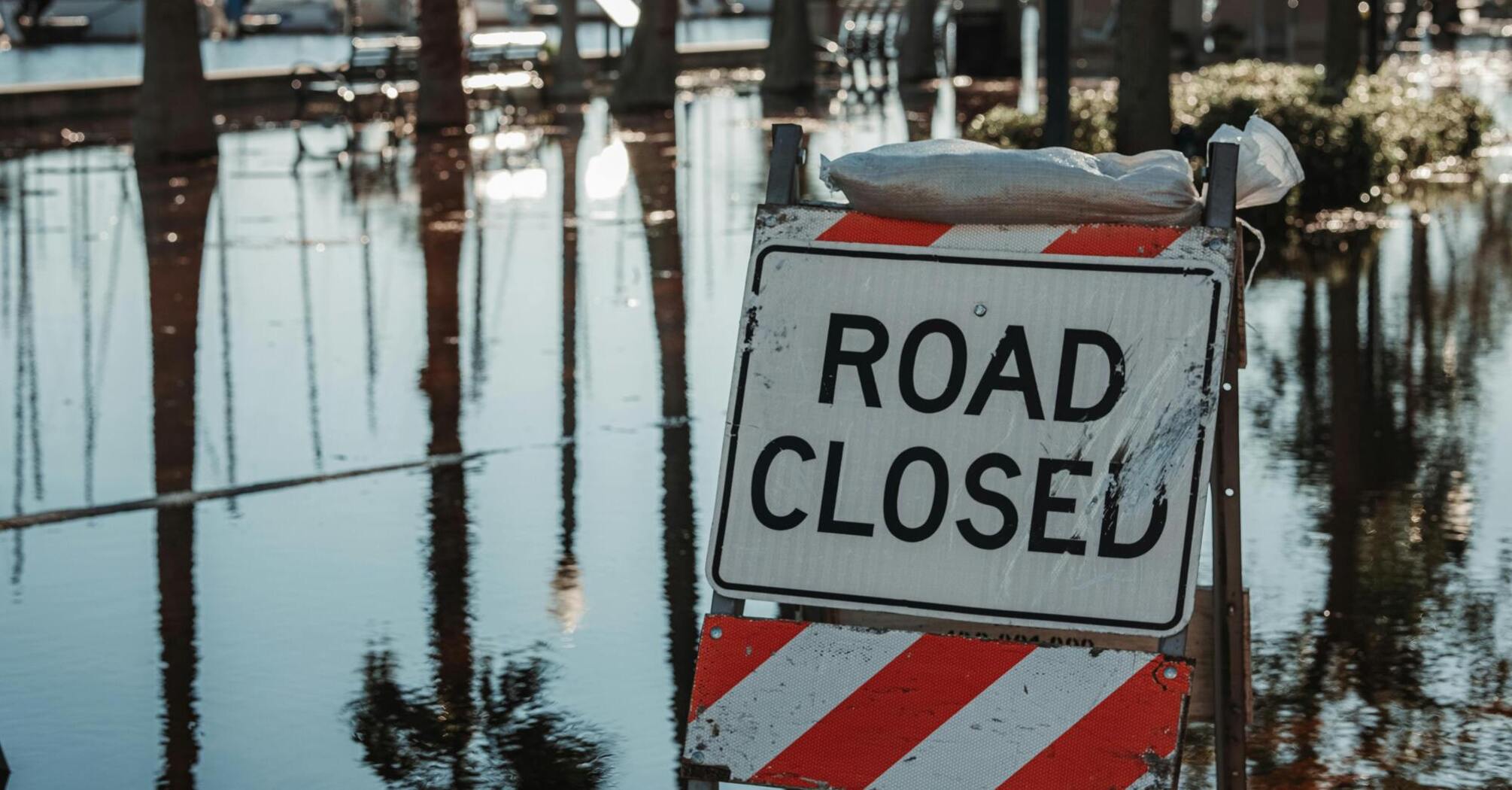 Road closed sign due to flooding near waterfront