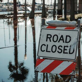 Road closed sign due to flooding near waterfront