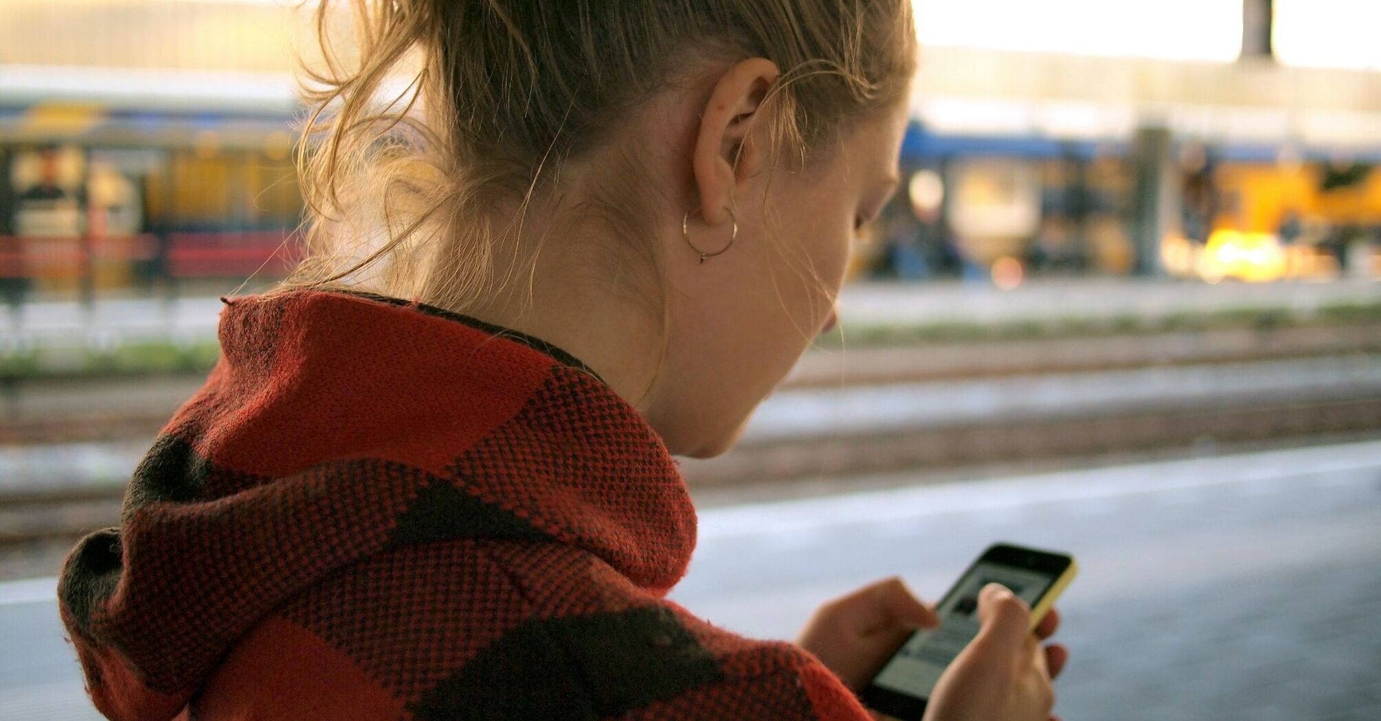 Person using a mobile phone while waiting at a train station