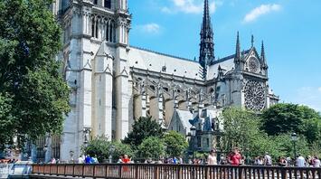 Notre Dame Cathedral viewed from across a bridge filled with pedestrians on a sunny day