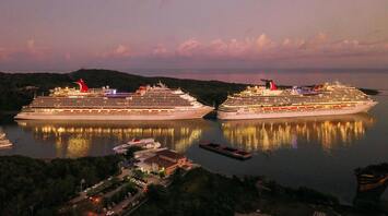 Two illuminated cruise ships docked at sunset