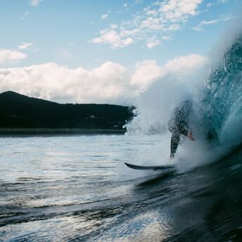 Surfer riding a wave near a mountainous coast