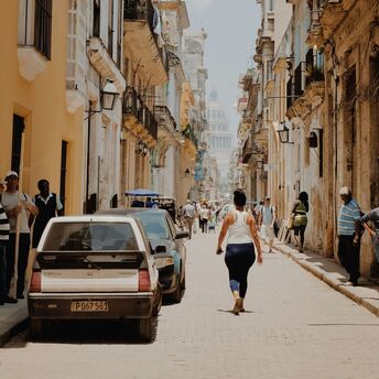 Narrow street in Havana with people walking under the sun