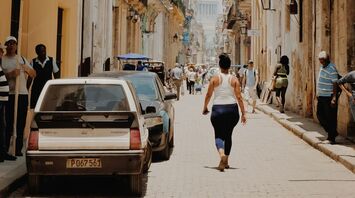 Narrow street in Havana with people walking under the sun