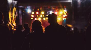 Silhouettes of people at a night event with colorful lights in the background
