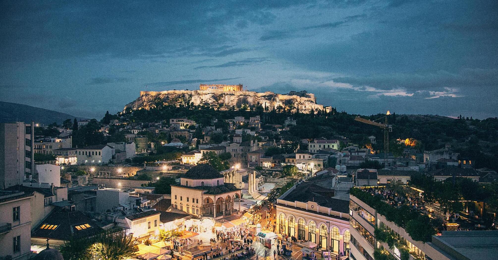 View of Athens at dusk with illuminated Acropolis and busy square