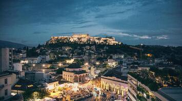 View of Athens at dusk with illuminated Acropolis and busy square