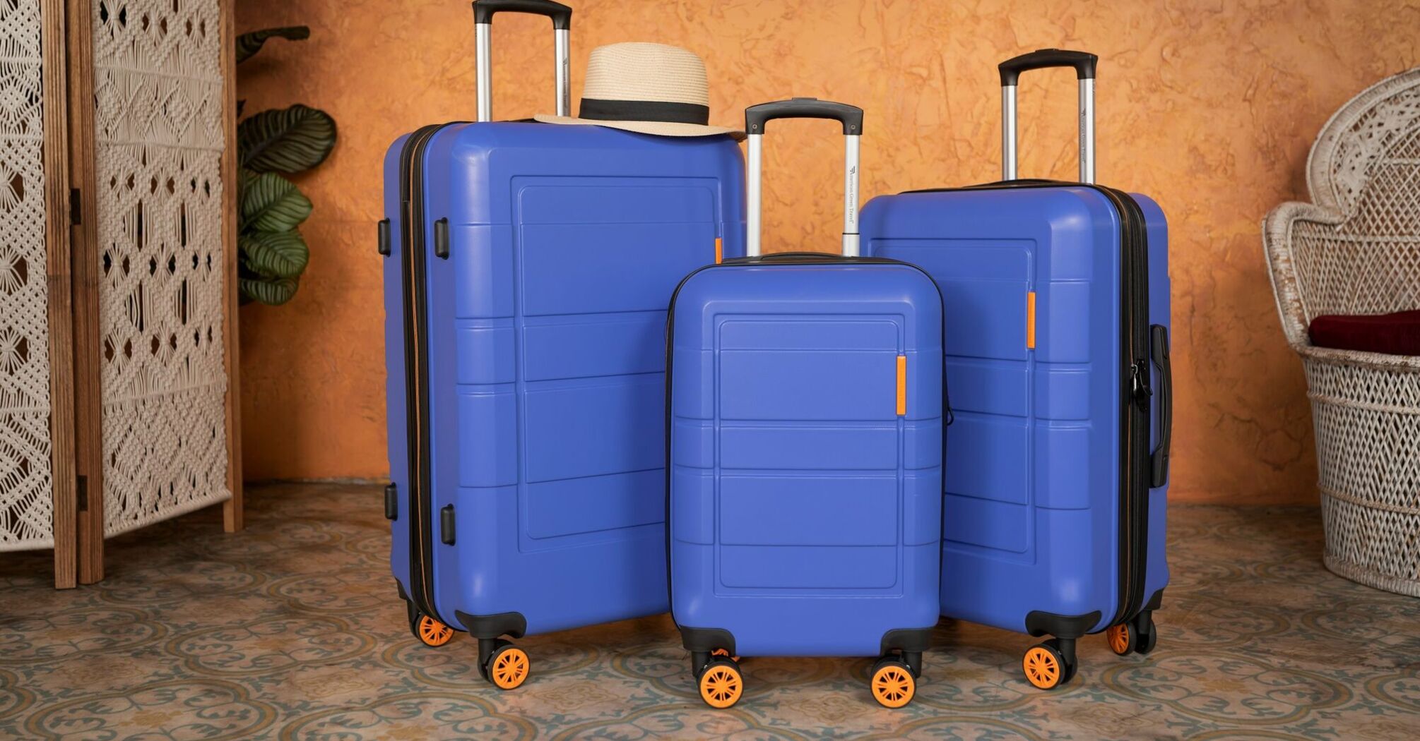 Three blue suitcases of different sizes, placed together, with a hat resting on top of the largest one