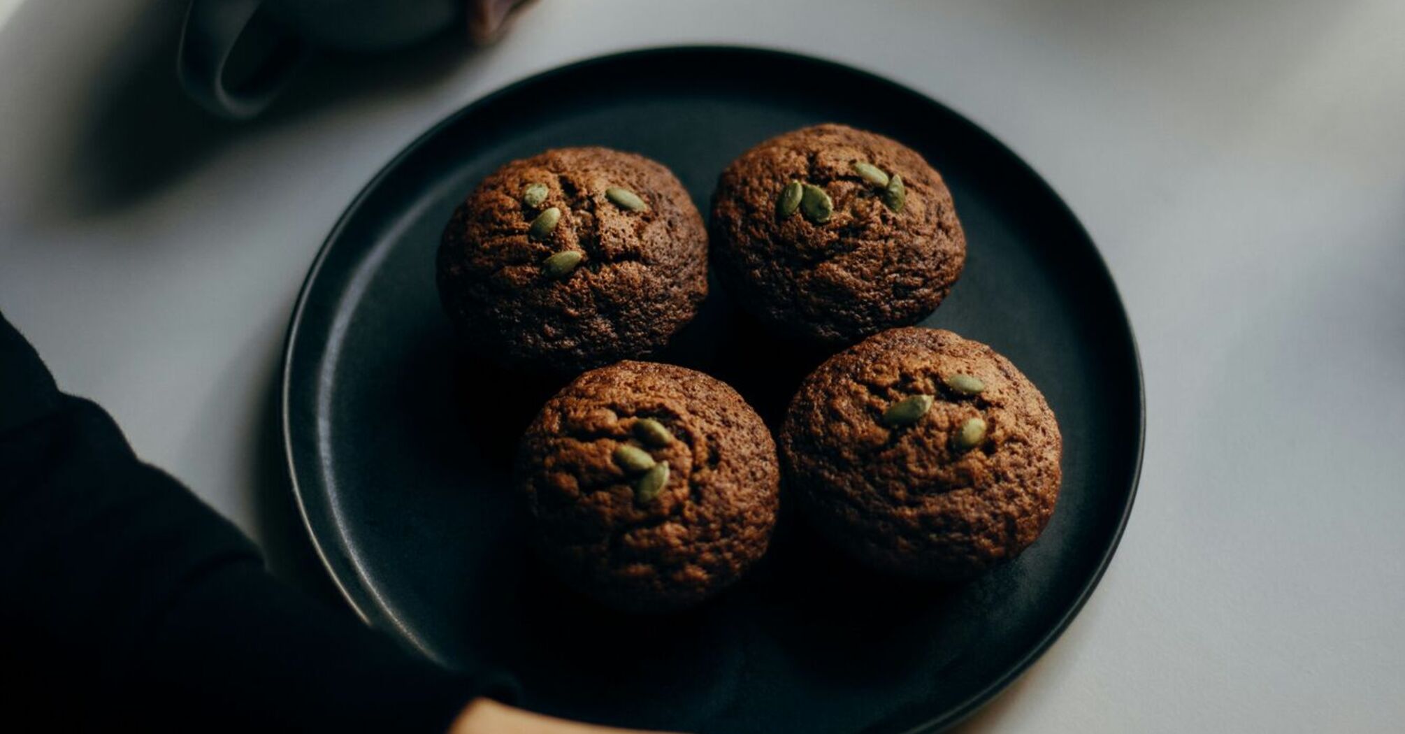 A person enjoying coffee with muffins