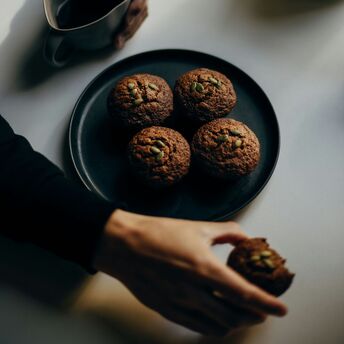 A person enjoying coffee with muffins