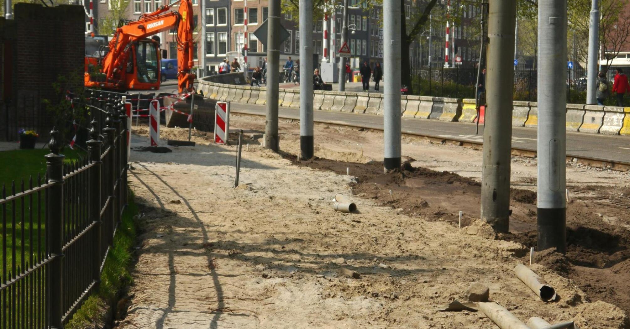 Heavy equipment operating at a road construction site, with barriers and excavated paths