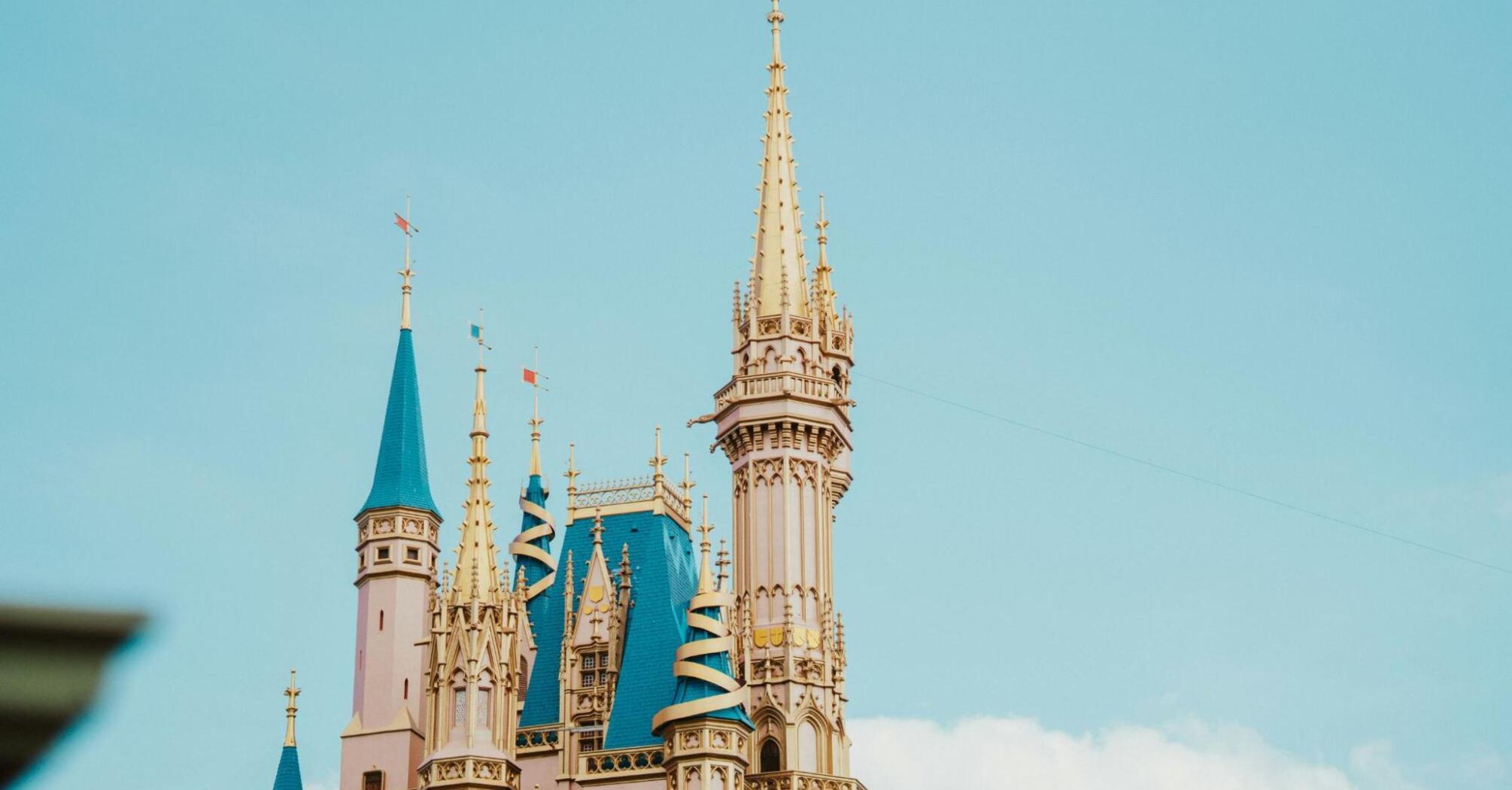 A tall, ornate castle tower with golden spires against a clear sky