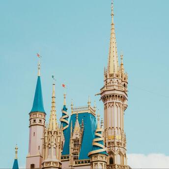 A tall, ornate castle tower with golden spires against a clear sky