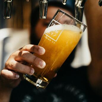 A person pours a glass of draft beer from a tap