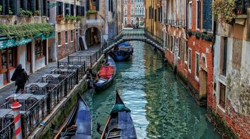 Quiet canal with gondolas and an empty café terrace in Venice