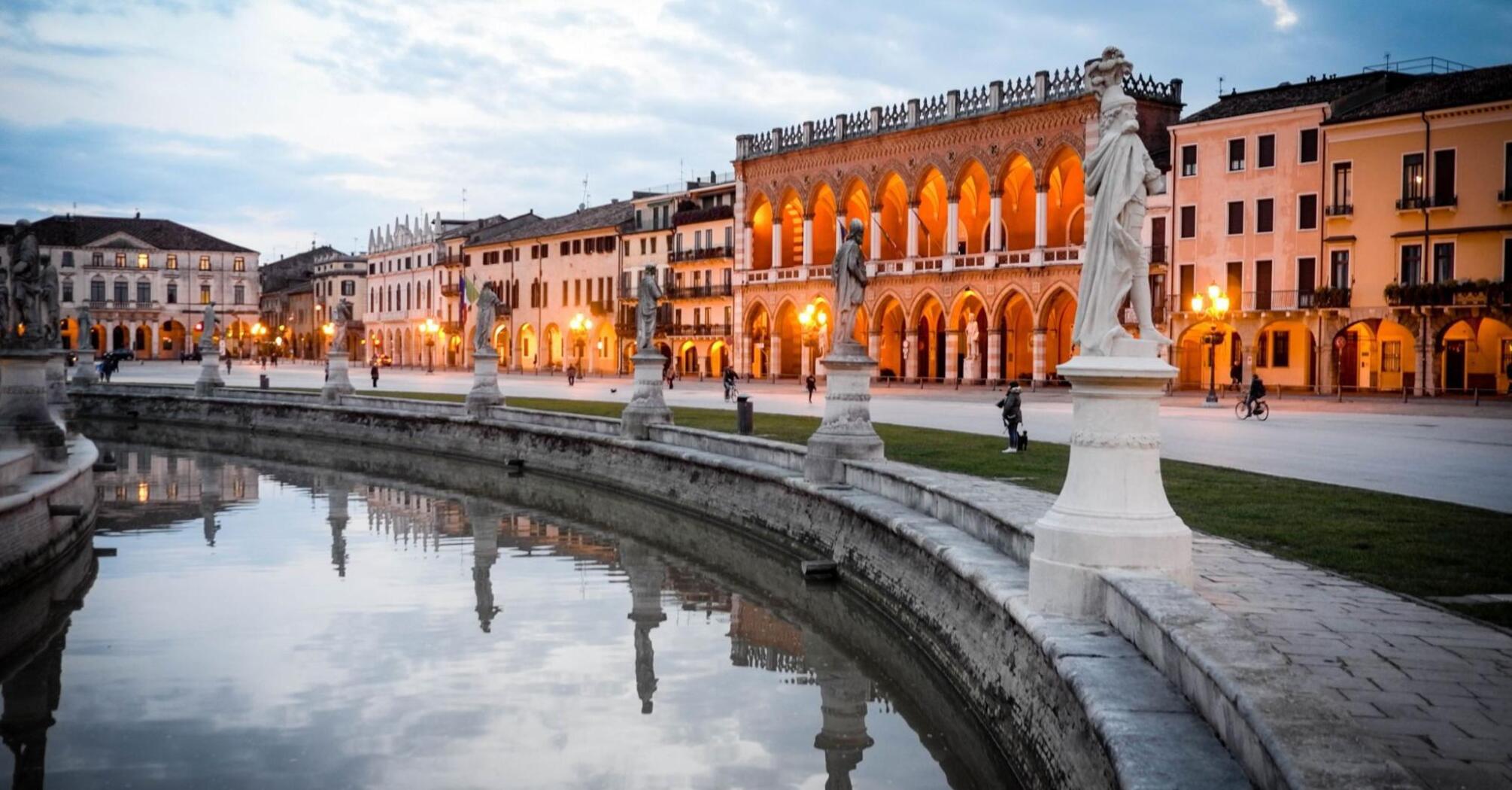 Evening view of Prato della Valle with statues and historic buildings in Padua, Italy