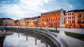 Evening view of Prato della Valle with statues and historic buildings in Padua, Italy