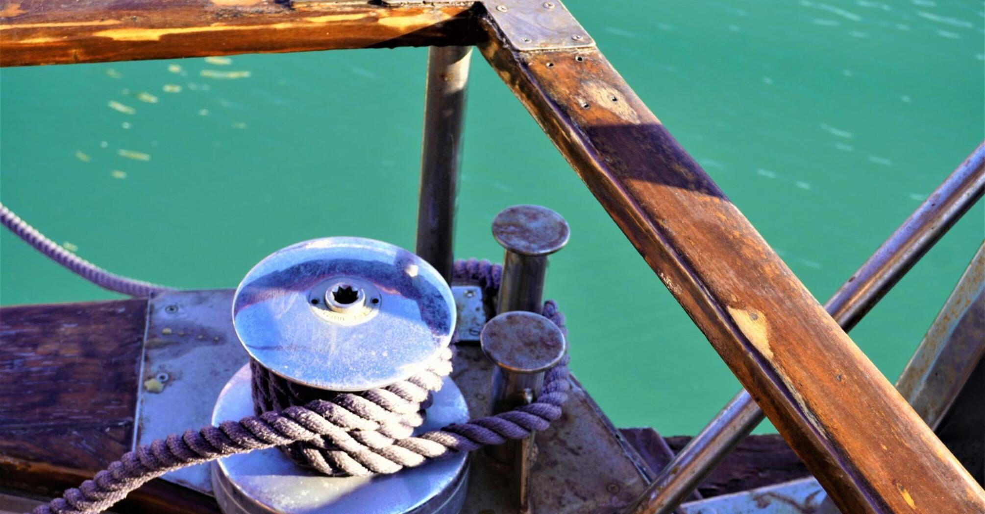 A close-up of a winch and rope on a wooden ship deck