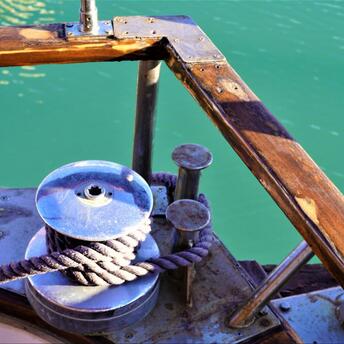 A close-up of a winch and rope on a wooden ship deck