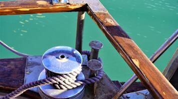 A close-up of a winch and rope on a wooden ship deck