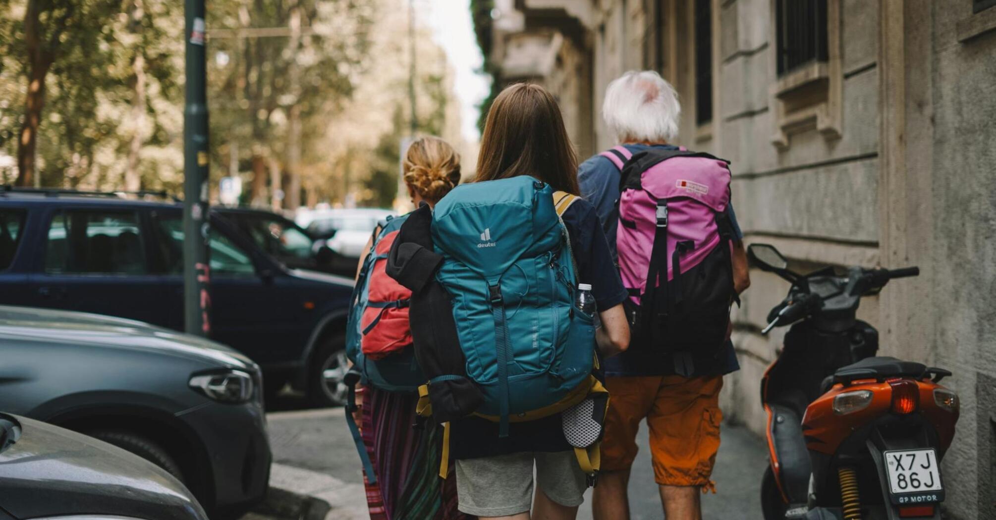 A group of travelers with backpacks walking along a city street