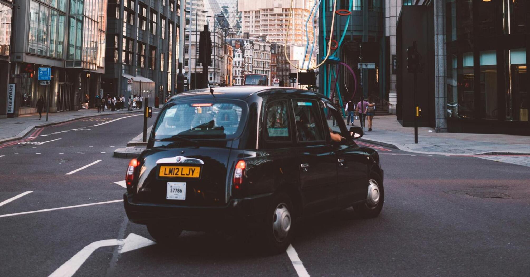 Black taxi on a London street with iconic skyscrapers in the background