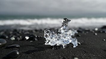 Piece of ice on a black sand beach with ocean waves in the background