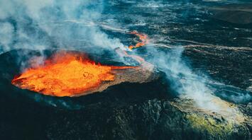 Aerial view of an active volcanic eruption with lava flowing across rugged terrain in Iceland