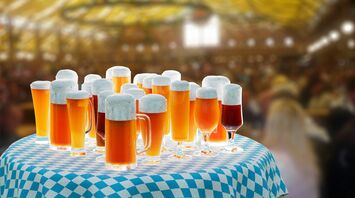 A table filled with glasses of beer under a Bavarian-style tent during Oktoberfest