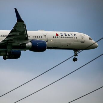 A Delta Air Lines plane approaching for landing, showing its landing gear extended and preparing to touch down